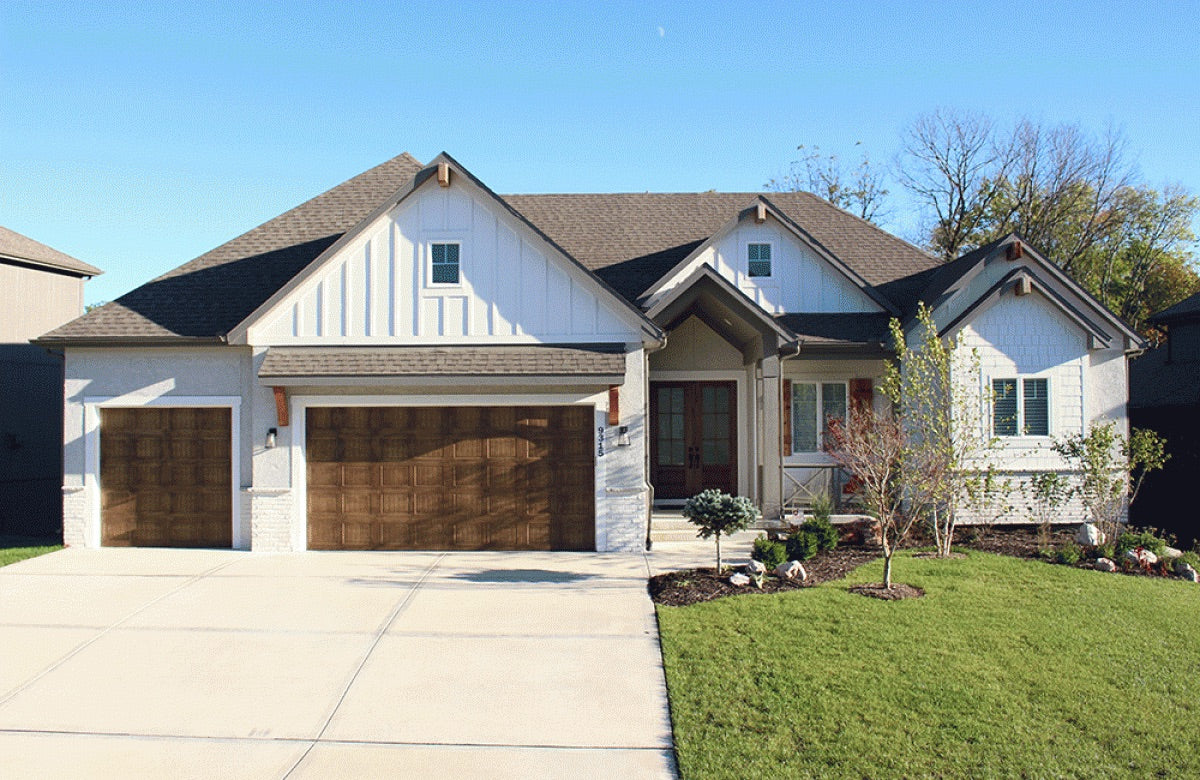 Front of a craftsman style custom house with front lawn and landscaping.