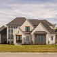 Front of a custom home in the European and Cottage style of architecture with front lawn and landscaping.