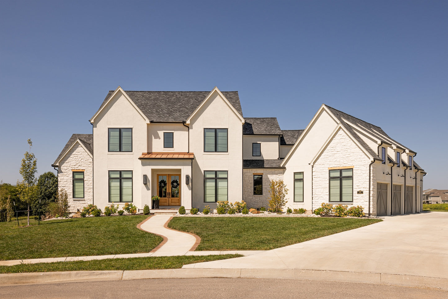 Front of a European and French Country style of custom home with front lawn and lancscaping.