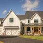 A front view of a modern farmhouse custom home with a green lawn.